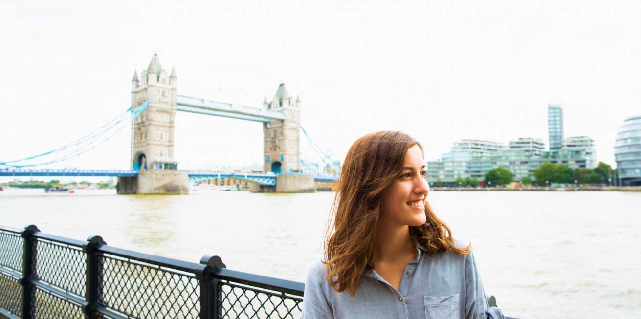 woman by river and large bridge